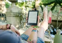 woman lying on chair holding tablet computer