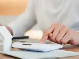 Homme avec une calculatrice et une mini maison