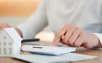 Homme avec une calculatrice et une mini maison
