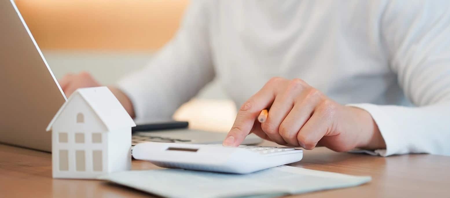 Homme avec une calculatrice et une mini maison
