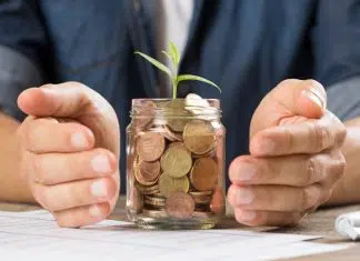 Mains qui protègent un bocal en verre rempli de pièces