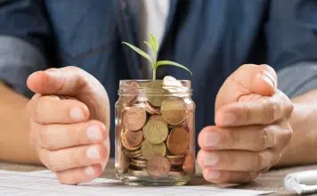 Mains qui protègent un bocal en verre rempli de pièces