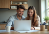 Jeune couple souriant à la cuisine avec documents financiers