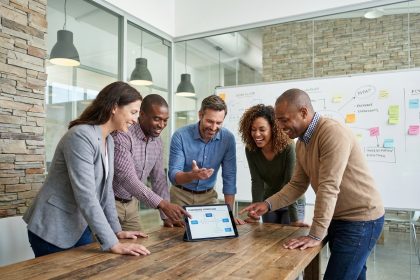 Groupe de professionnels au bureau discutant autour d'une tablette