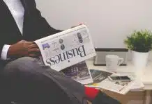 person sitting near table holding newspaper